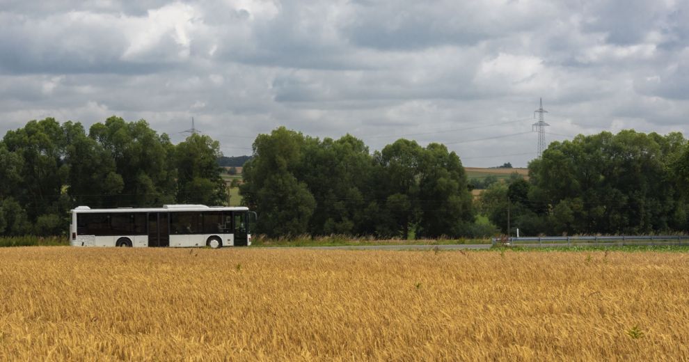 Landwirtschaftlich geprägte Landschaft mit vorbeifahrenem Bus.