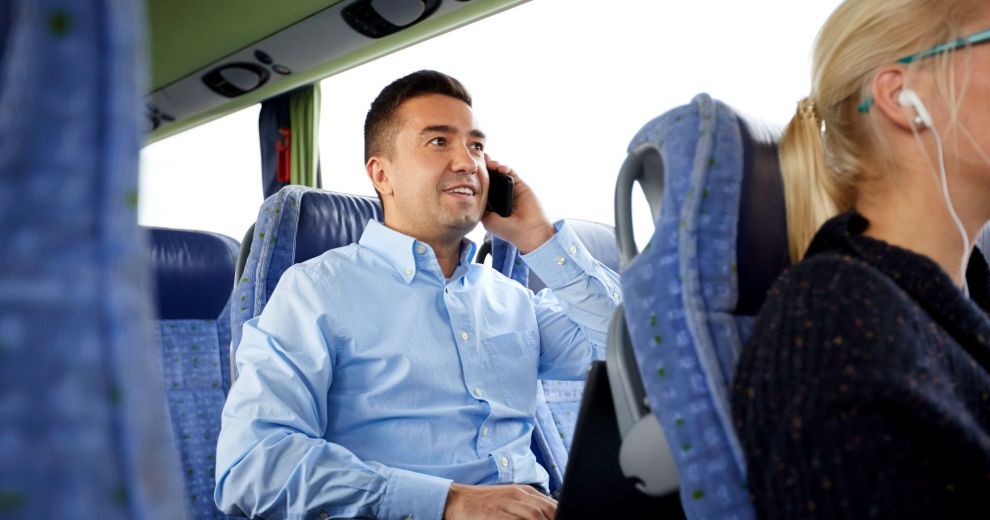Mann mit Smartphone und Laptop im Bus.